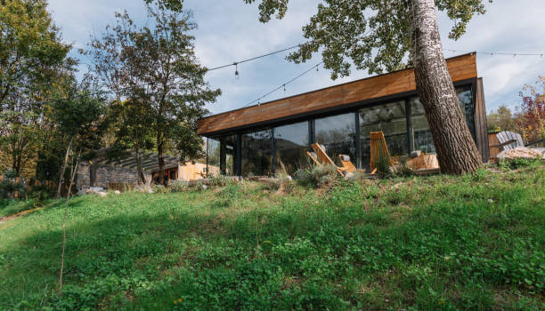Photo of a charming wooden cabin nestled on the riverbank, featuring a sliding glass door designed to bring the beauty of nature right into this living space