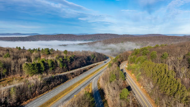 istock Nearly empty highway on a sunny day descending into thick fog, cloud cover, creating a mysterious and serene landscape. 2190131210