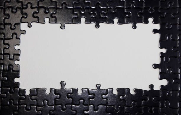 Close up of black puzzle pieces with white blank space for text.
