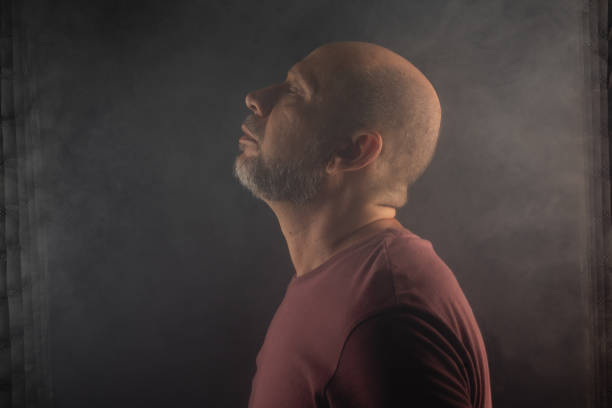 istock Bald and bearded man looking up. Isolated on smoky black background. 2190143305