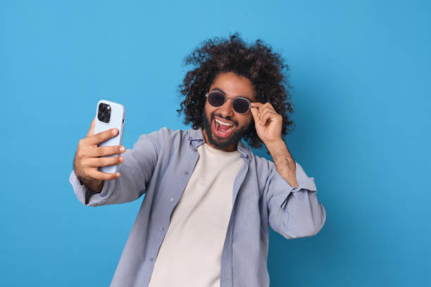 istock Joyful Man Takes a Selfie Against a Vibrant Blue Background 2190148686