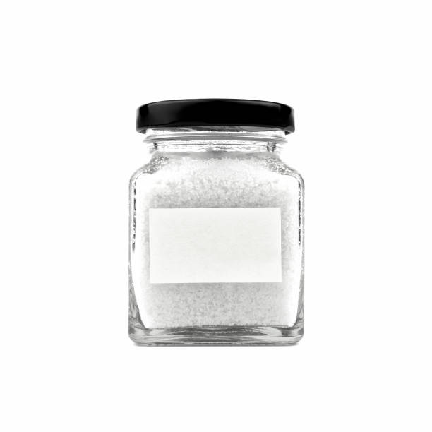 istock Salt in a glass bottle isolated on white background. Empty white stick note paper and black lid. Modern and stylish. Close up. 2190154653