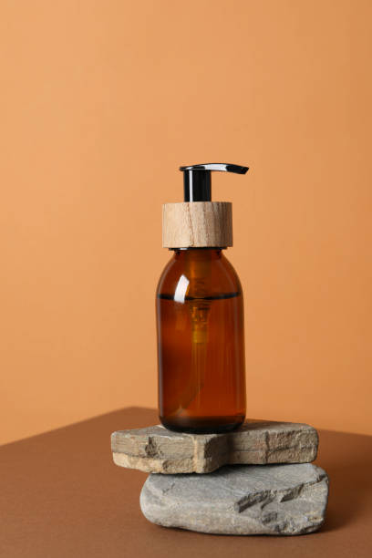 istock Dispenser on stones on wooden table, orange background 2190155235