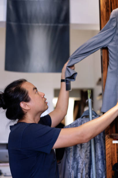 istock Man Inspecting Gray Suit Jacket in Clothing Store with Focused Expression 2190159960