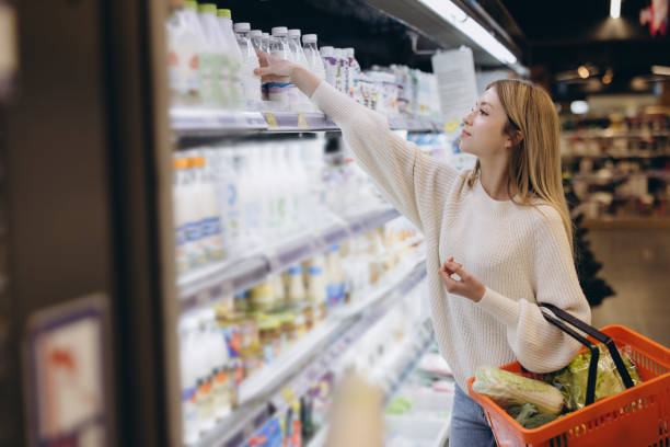 Customer choosing water bottle in supermarket refrigerator section