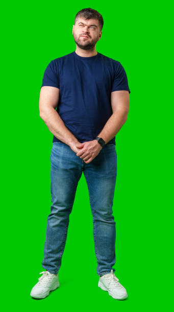 istock Man standing with a thoughtful expression in a casual outfit against a green background 2190170081