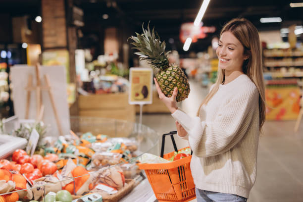 istock Smiling customer choosing pineapple in supermarket fruit and vegetable section 2190171221