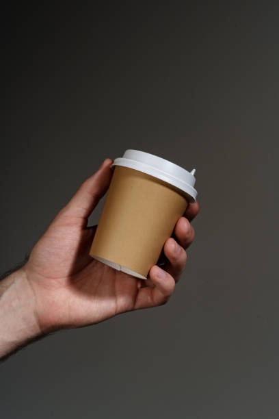 istock A hand holding a disposable coffee cup against a dark background 2190172802
