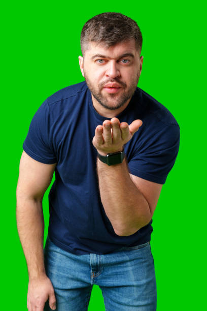 istock A man blowing a kiss while standing against a bright green backdrop in a casual outfit 2190173912