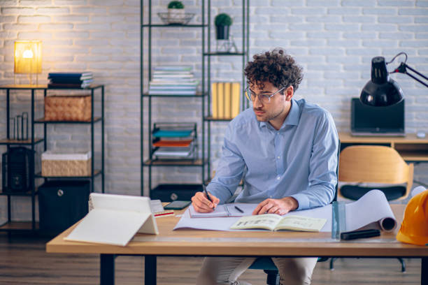 istock Architect concentrating on paperwork, managing projects and working remotely in a bright home office 2190175089