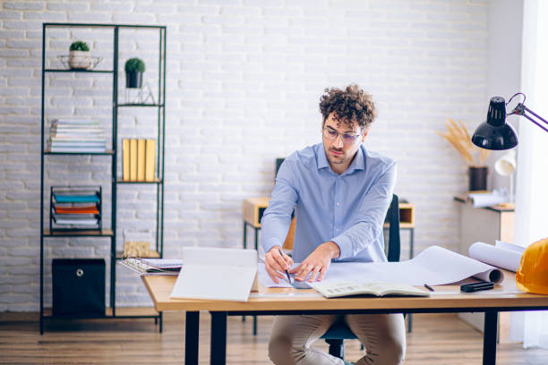 istock Architect concentrating on paperwork, managing projects and working remotely in a bright home office 2190175185