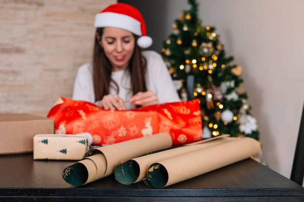 istock A woman is sitting at a table with a Christmas tree in the background. 2190177554
