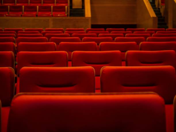 istock Empty red theater seats in dimly lit auditorium. 2190180493