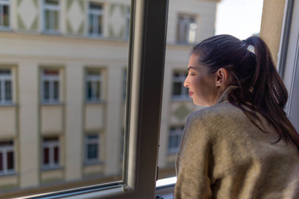 istock Woman looking through the window. 2190181343