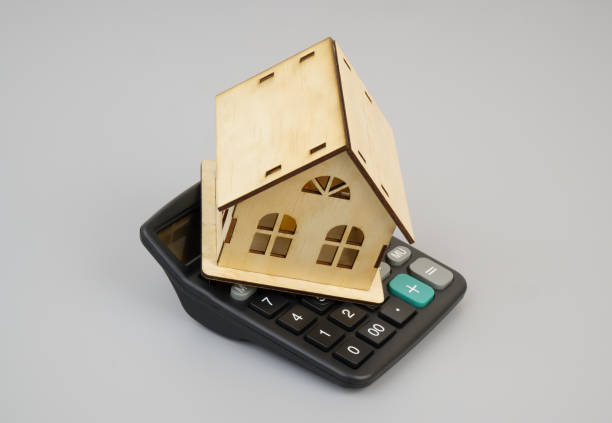 istock Wooden house on calculator on gray background. 2190182335