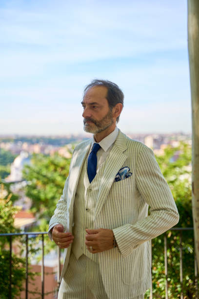 Caucasian man over 50 in striped suit posing outdoors with scenic background