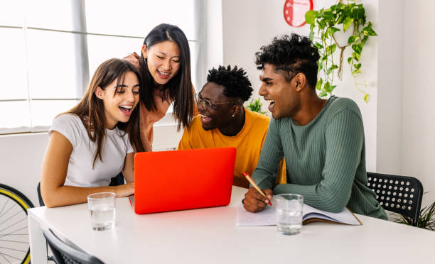 Happy high school students learning together using laptop computer at home stock photo