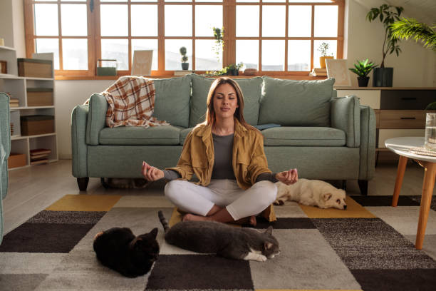 istock Young woman meditating at home with her pets 2190191103