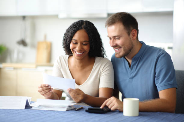 istock Happy couple reading bank statement in the kitchen 2190196012