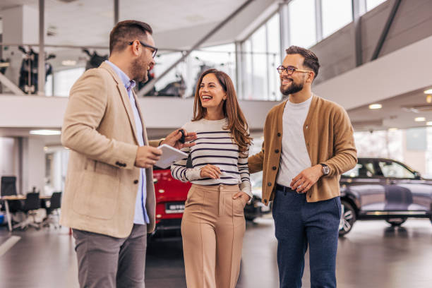 istock A salesman talking with customers in a car dealership. 2190197603