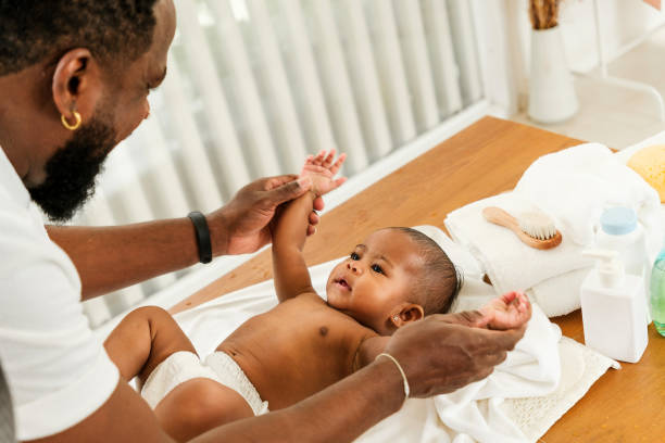 istock A joyful moment between a father and his baby during a playful interaction on a changing table. Happy diversity family and newborn bathing concept. 2190198599