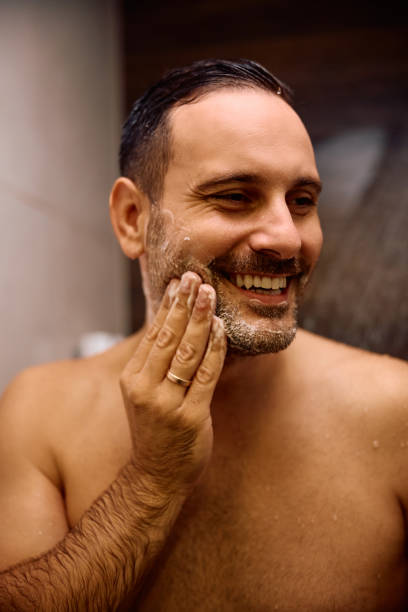 istock Happy man using skin care product while showering in the bathroom. 2190202046