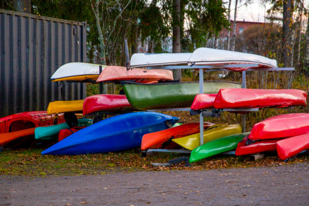 Arrangement of colorful kayaks stacked neatly outdoors. Concept of adventure enthusiasts, water sports, and recreational activities