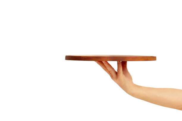 istock Man hand holding a brown round wooden tray on a blue background with copy space 2190206164