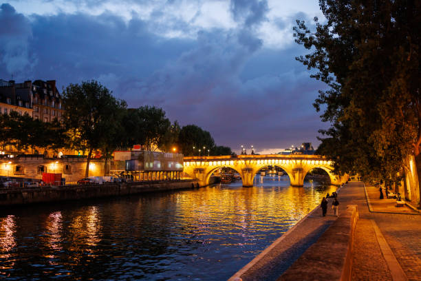 istock Illuminated bridge with arches on the Seine River from the pier under the cloudy sky at dusk in Paris 2190209428