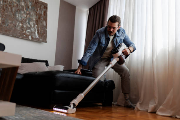 istock Man cleaning house with wireless vacuum cleaner 2190211780
