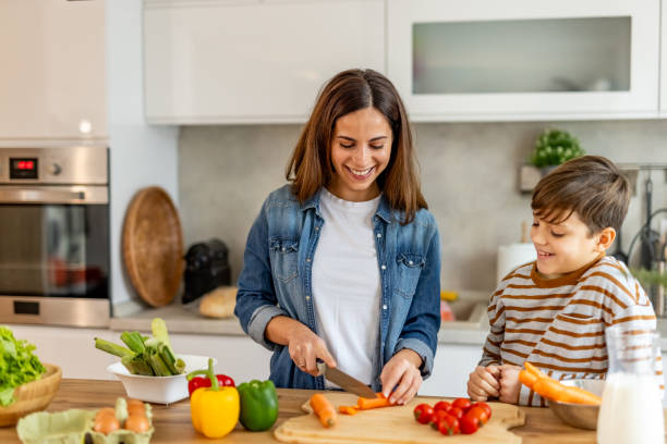 istock Happy mother slicing carrots while preparing healthy meal with her son in a modern kitchen 2190213040