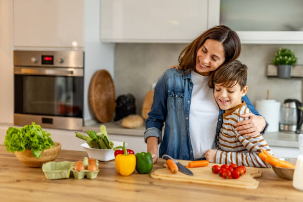 istock Mother lovingly embraces her son while preparing healthy meal with fresh vegetables in a modern kitchen, enjoying quality time together 2190213075