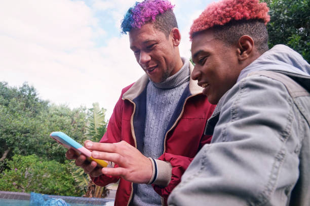 Smiling friends looking at smart phone in garden