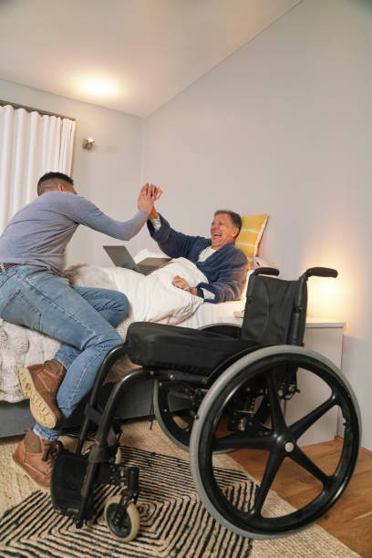 istock Man and disabled friend sitting in bed giving high five 2190214611