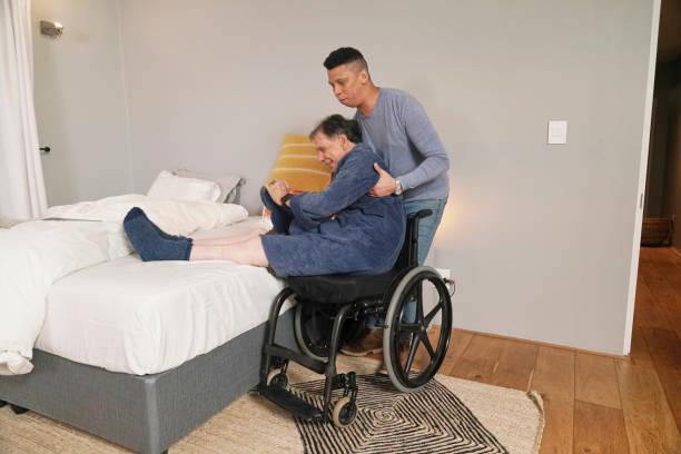 istock Man helping disabled friend getting out of bed 2190214847
