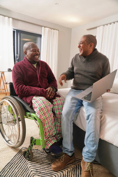 istock Man in wheelchair and his assistant using tablet in bedroom 2190214956
