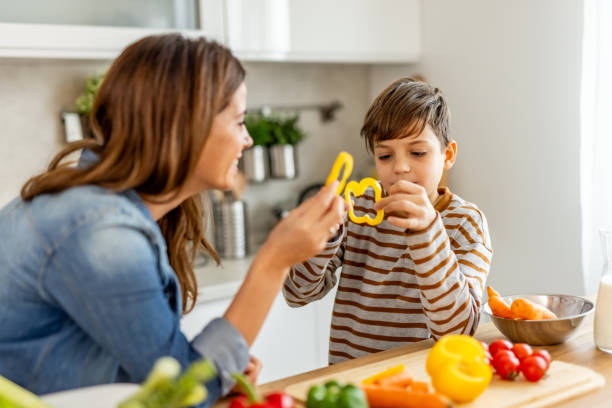 istock Mother and son bonding while slicing yellow bell peppers for a nutritious meal in a well-lit kitchen 2190215312