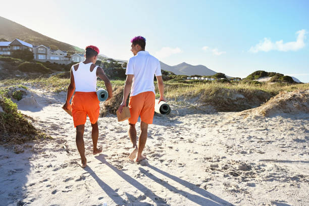 istock Men with yoga mats on beach 2190215592