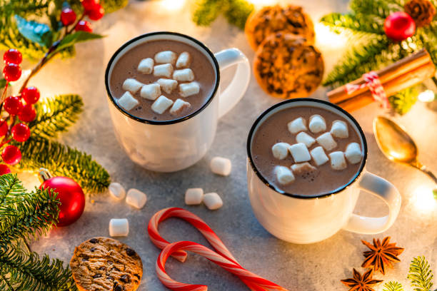 istock Two hot chocolate marshmallow mugs and chocolate chips cookies on decorated Christmas table 2190215876