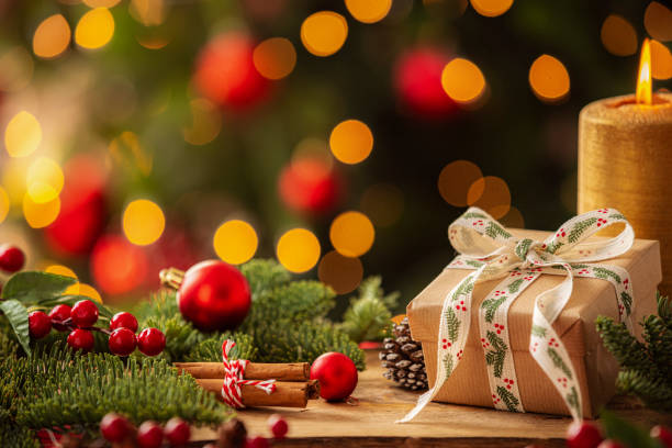 istock Christmas present on a cozy table with Christmas decore candle and illuminated tree at background 2190215895