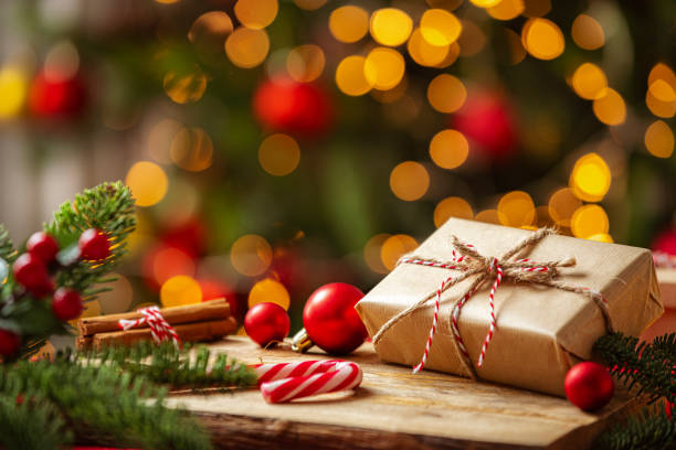 istock Christmas present on a cozy table with defocused Christmas tree at background 2190215904