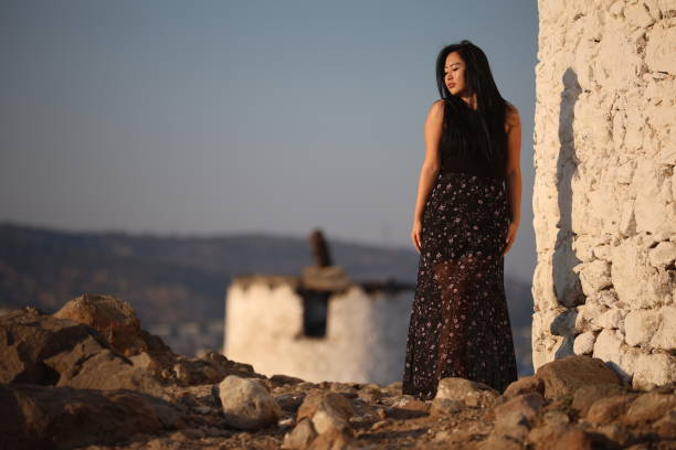 A joyful young Asian woman embraces the breathtaking beauty of her surroundings during the golden hour.