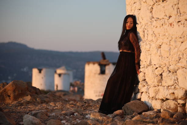 A joyful young Asian woman embraces the breathtaking beauty of her surroundings during the golden hour.