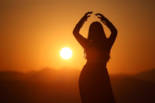 A joyful young Asian woman embraces the breathtaking beauty of a stunning sunset.
