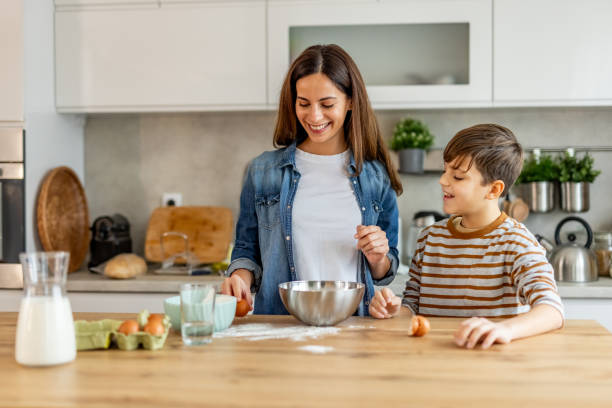 istock Mother and son joyfully preparing cake ingredients, cracking eggs and mixing flour in their modern kitchen 2190221239