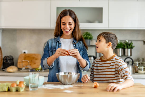 istock Happy mother and son cracking eggs into a bowl while baking in the kitchen, enjoying quality time together 2190221304