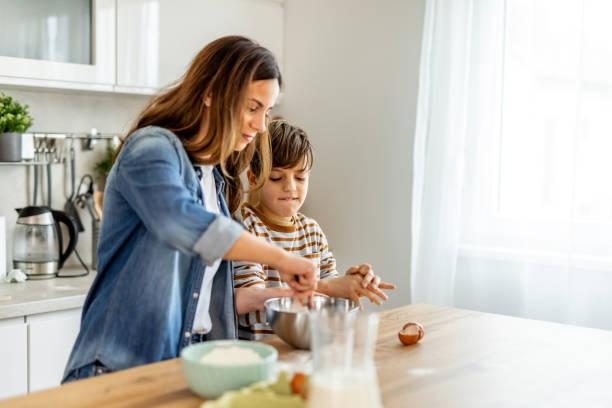 istock Mother and son joyfully preparing a cake together in a bright kitchen, whisking ingredients in a bowl and sharing laughter 2190221357