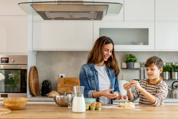 Mother and son share a joyful moment while baking cookies and kneading dough in a sleek, contemporary kitchen