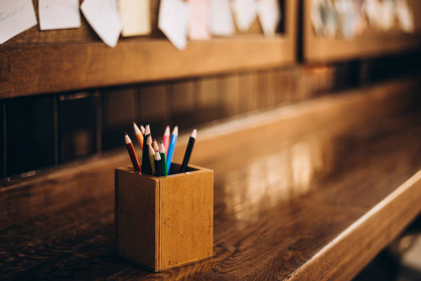 Box with colorful pencils on background of various sticky post it notes on a wooden background inside a cafe. Copy space. Sticky notes with good job text. Motivation and positive wishes concept.