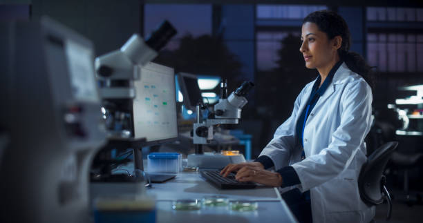 istock Hispanic Female Scientist Working on a Computer in the Evening. Specialist Using a Gene Sequencing Online Software. Advanced Biotechnology Lab in a Medical Research and Development Center 2190228022